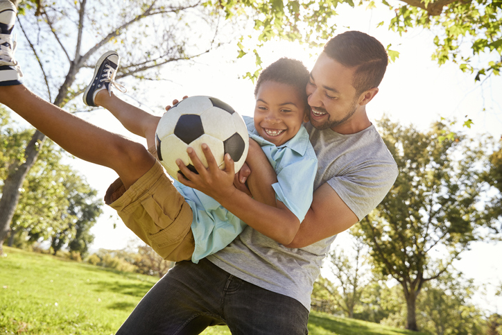 Father And Son Playing Soccer In Park Together Father And Son Playing Soccer In Park Together