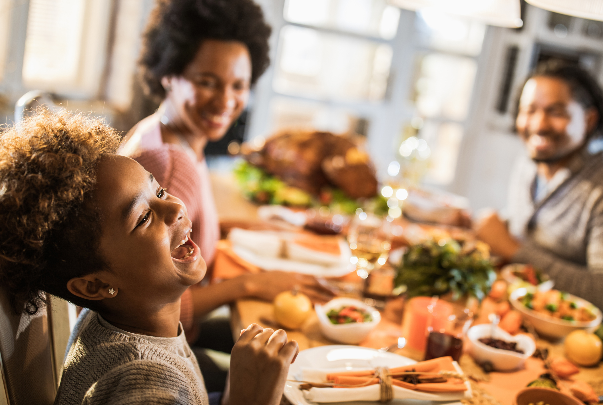 Cheerful African American girl with her parents at dining table. Cheerful African American girl with her parents at dining table.