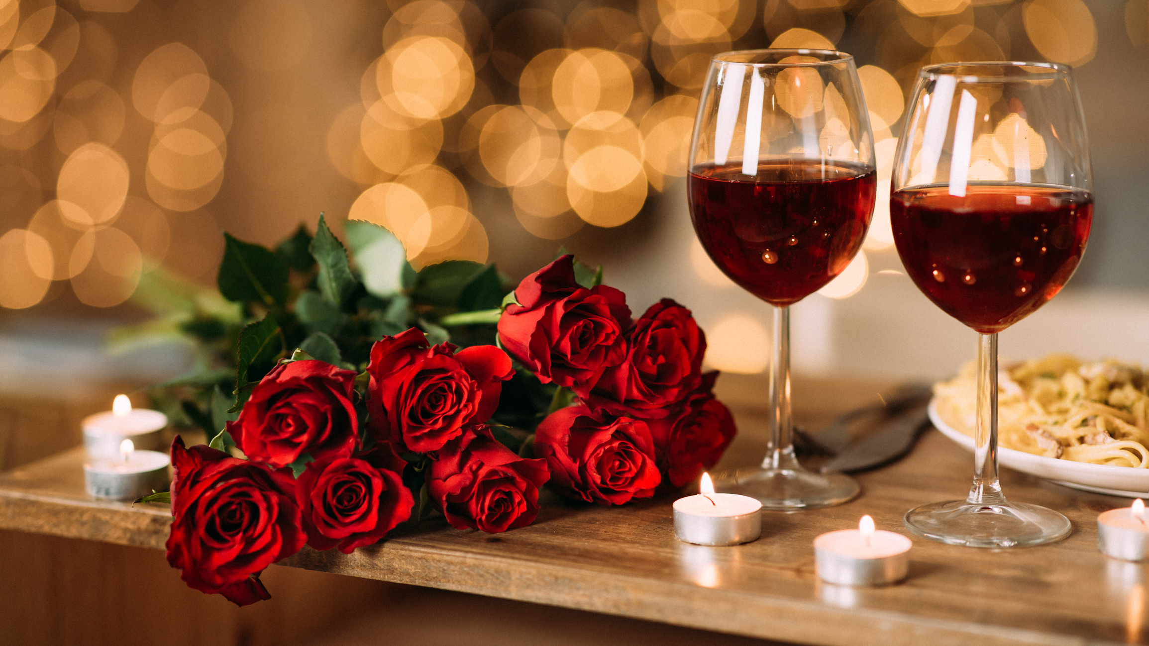 Roses, two glasses of red wine and candles on desk