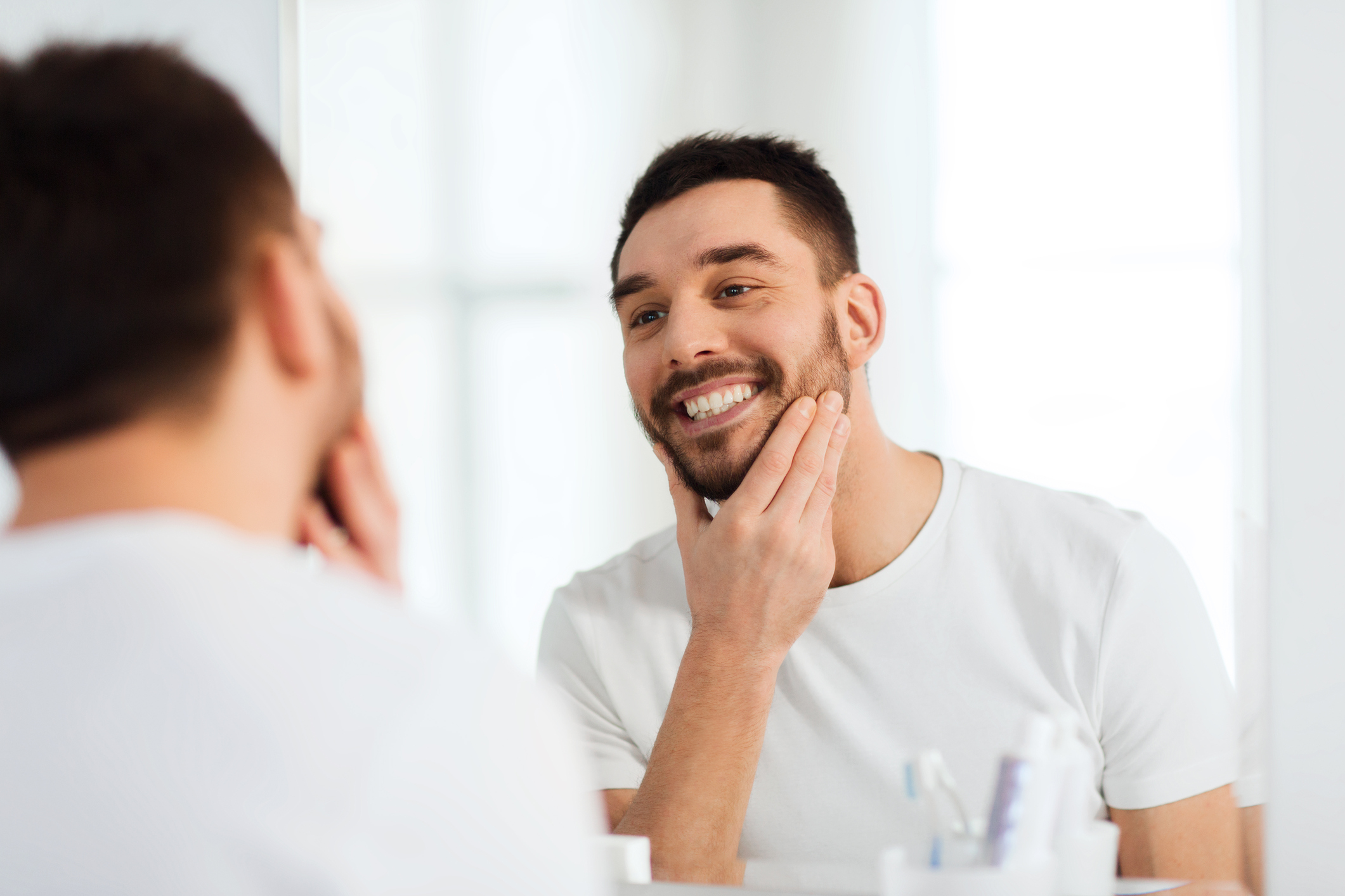 happy young man looking to mirror at home bathroom happy young man looking to mirror at home bathroom