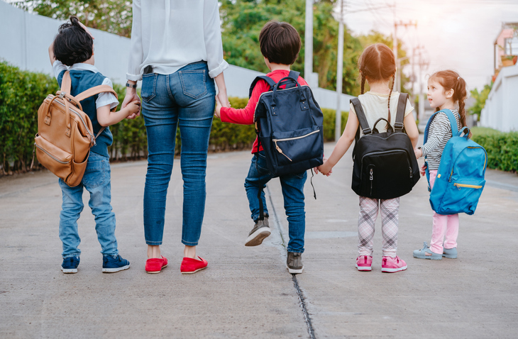 Mother and pupil and kids holding hands going to school in first class with schoolbag or satchel walking to school bus, Parent and son,sister preschool